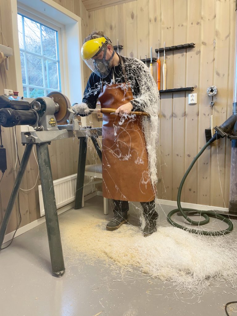 A person in a hard hat and apron using a hammer.