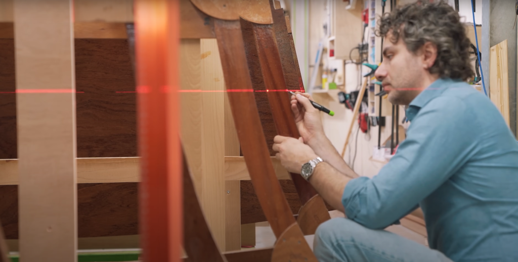 man marking out the build of his boat with lasers for guidance