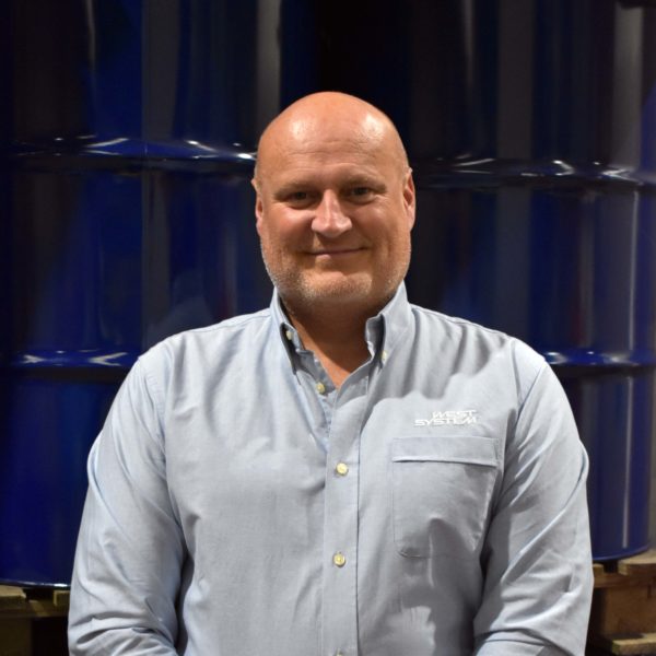 Headshot of Wessex Resins employee Martin Pickett in front of barrells