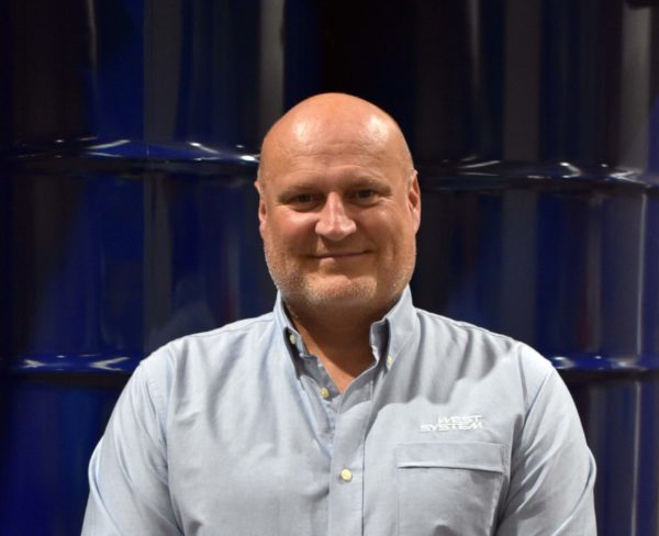 Headshot of Wessex Resins employee Martin Pickett in front of barrells