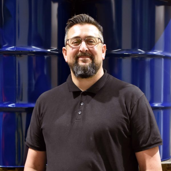 Headshot of Wessex Resins employee Paul Luffman in front of barrells